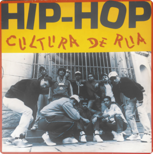 Capa de álbum com fotografia em preto e branco de um grupo de homens sentados, agachados e em pé, em frente ao portão de uma casa. Alguns deles usam bonés e correntes no pescoço.