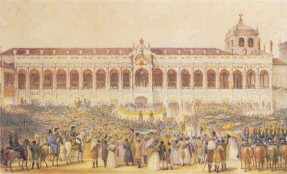Gravura representando um palácio luxuoso com varandas que dão vista para uma praça ampla. Uma multidão está reunida na praça, aclamando um grupo de cortesãos em torno do imperador Dom João Sexto, que está em um terraço diante elevado na entrada do palácio.
