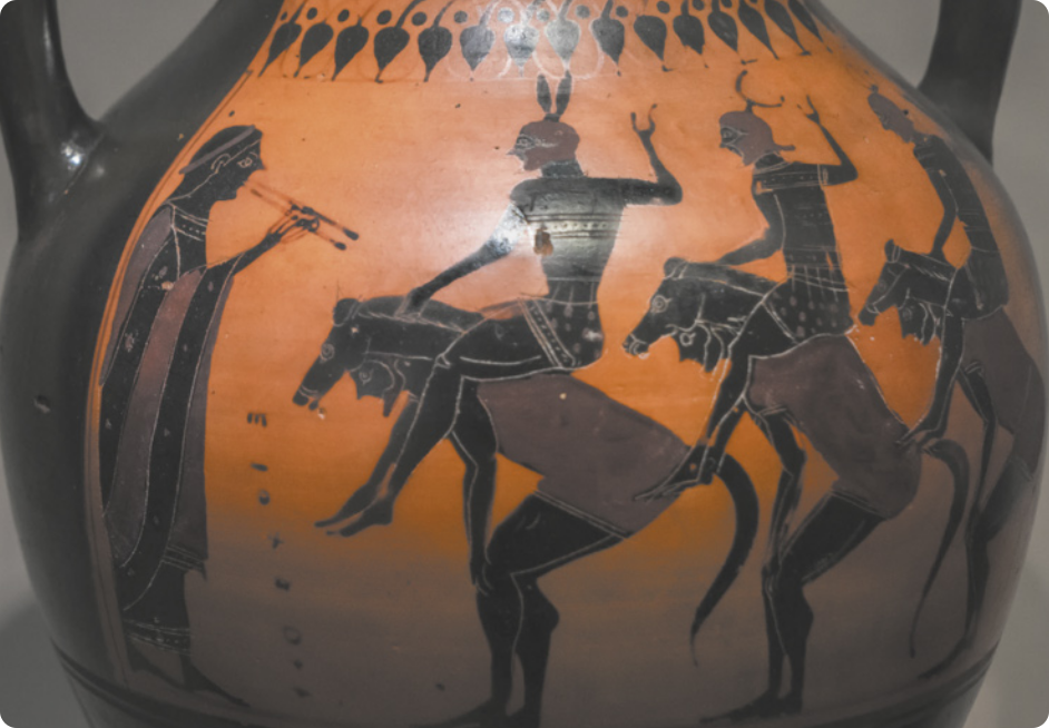 Fotografia de um vaso de cerâmica com uma pintura representando uma fila de homens fantasiados de cavalos, com o corpo inclinado para a frente, carregando homens de capacete nas costas. Eles estão diante de uma pessoa tocando uma flauta.