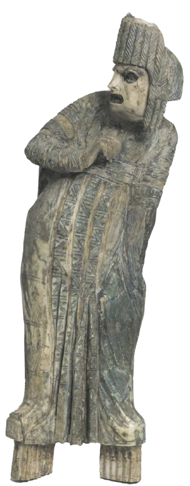 Fotografia de escultura representando um homem em pé sobre sapatos com grandes plataformas, vestido com uma túnica e um chapéu. Ele está com o corpo inclinado para o lado, com uma das mãos em frente ao peito, junto ao corpo, com a expressão facial colérica.