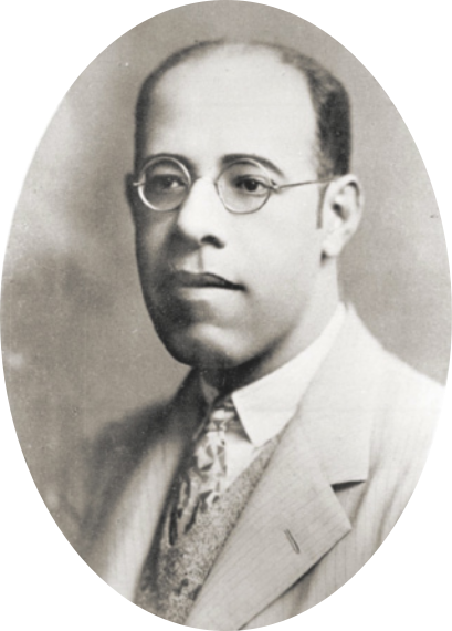 Fotografia em preto e branco com retrato de Mário de Andrade. Ele é um homem calvo, de óculos, com o queixo proeminente e largo, vestido com terno e gravata.
