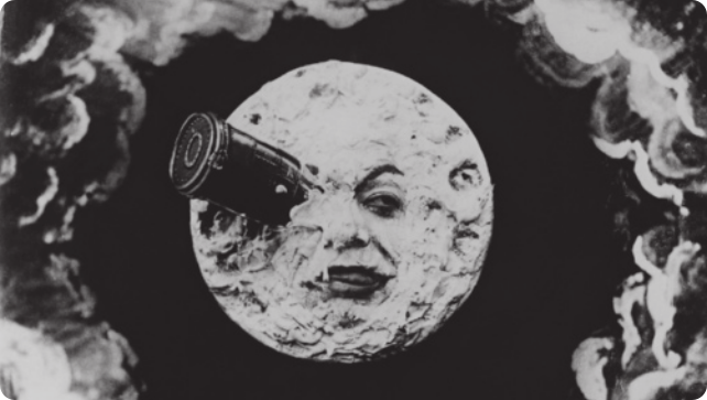 Imagem de uma representação da Lua com um rosto humano, com uma espaçonave de formato cilíndrico pousada sobre um dos olhos do rosto.
