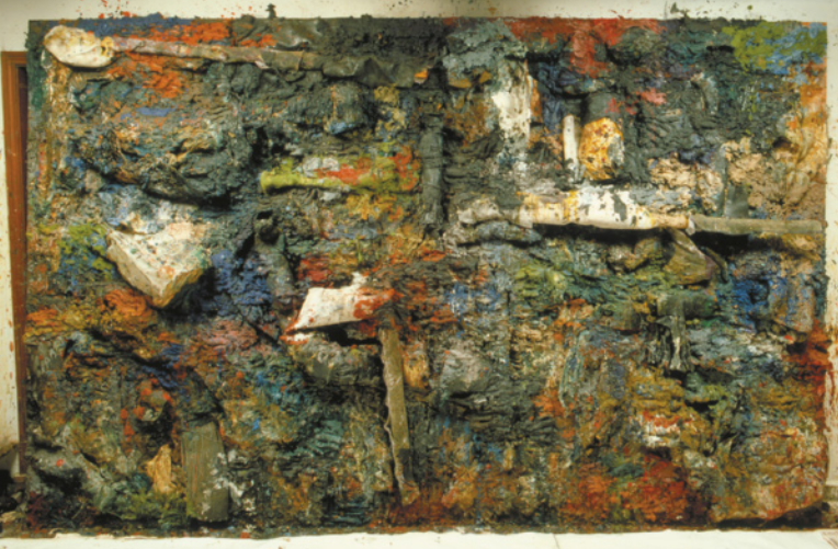 Pintura com diversos objetos e tipos de materiais colados à superfície do quadro, em meio a uma massa espessa de tintas de diversas cores.