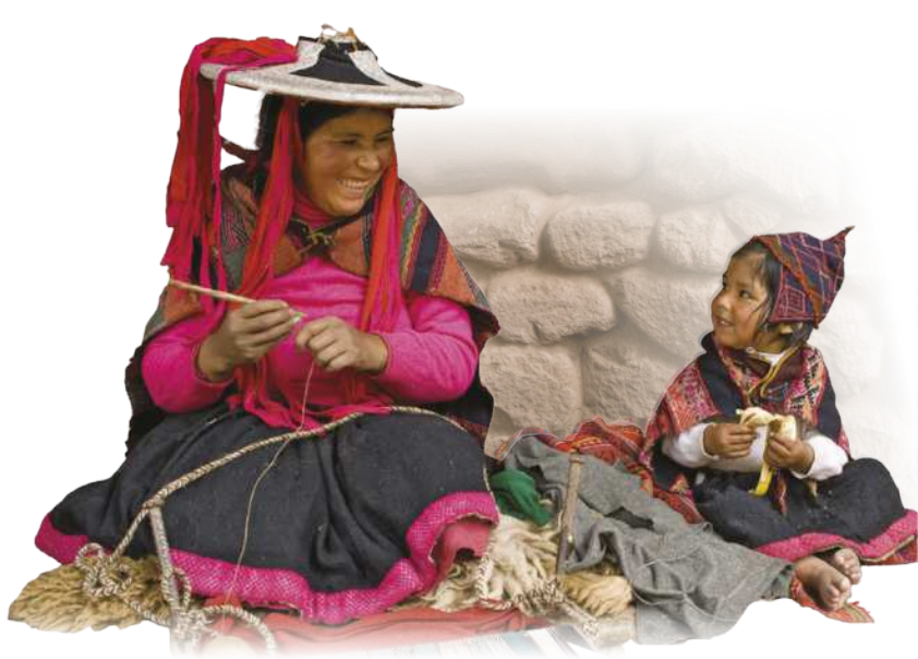 Fotografia de uma mãe e sua filha. Elas são indígenas, estão sentadas lado a lado no chão de pernas cruzadas, sorrindo uma para a outra. A mulher está costurando usando uma agulha grossa de madeira e um fio. Veste saia longa, camiseta de manga comprida, chapéu com lenço e uma capa sobre os ombros. A menina está segurando uma banana, tem vestes semelhantes às da mãe, porém usa um gorro no lugar do chapéu. Suas roupas são coloridas.