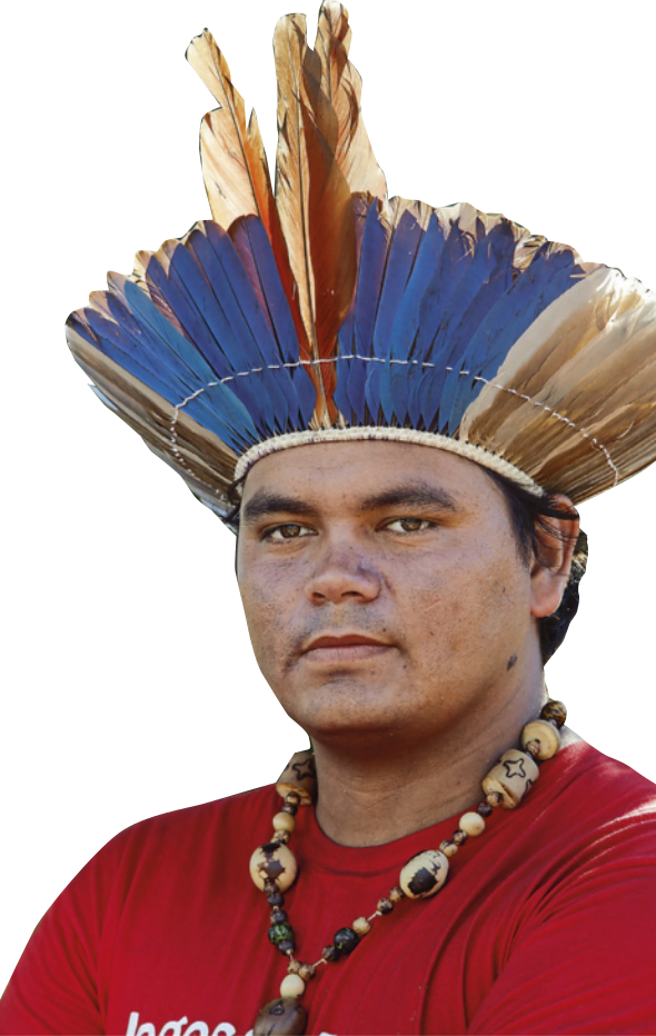 Fotografia de um homem indígena de cabelo curto, veste camiseta, colar e cocar.