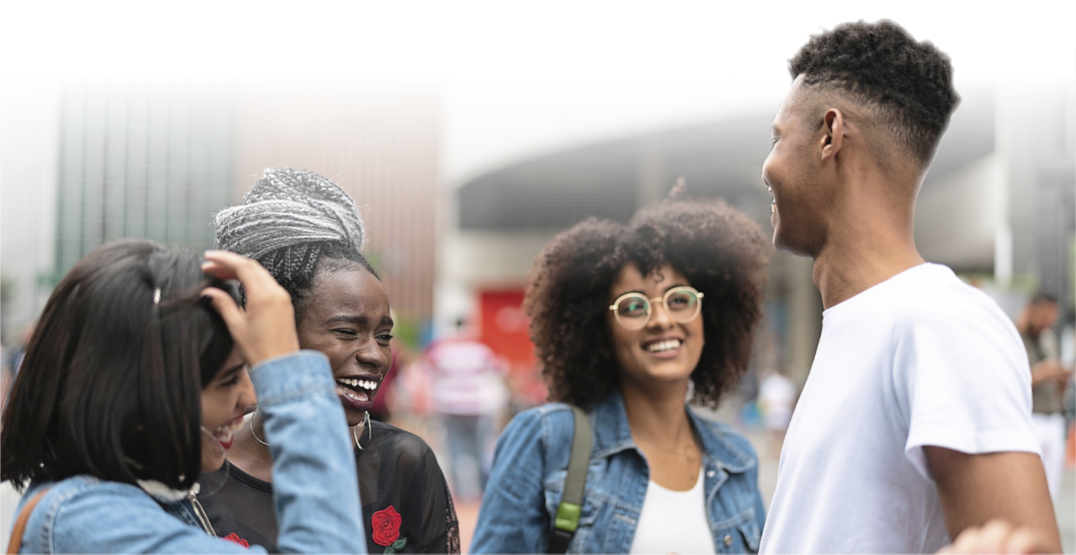 Fotografia de quatro jovens, três mulheres e um homem, em uma semi roda. Todos estão sorrindo.