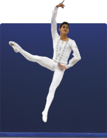 Fotografia de um bailarino, homem de pele clara e cabelos curtos. Está fazendo um salto, tem uma das mãos na cintura e a outra estendida acima da cabeça. Uma das pernas está levantada e estendida à lateral do corpo. Usa sapatilhas, camisa e calça coladas ao corpo.