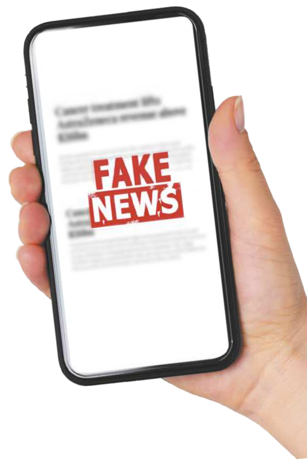 Fotografia da mão de uma pessoa segurando um smartphone. No centro da tela, está escrito 'Fake News' em destaque, sobre uma notícia que está desfocada.