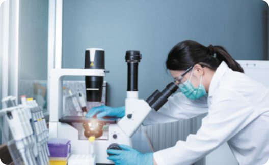 Fotografia de mulher cientista observando amostra em microscópio eletrônico em laboratório.