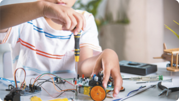 Fotografia de criança montando manualmente um carrinho elétrico.