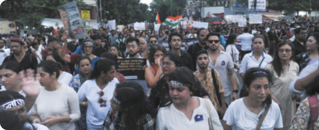 Fotografia de muitas pessoas andando em protesto. Algumas estão com faixas na cabeça. Há cartazes e bandeira.