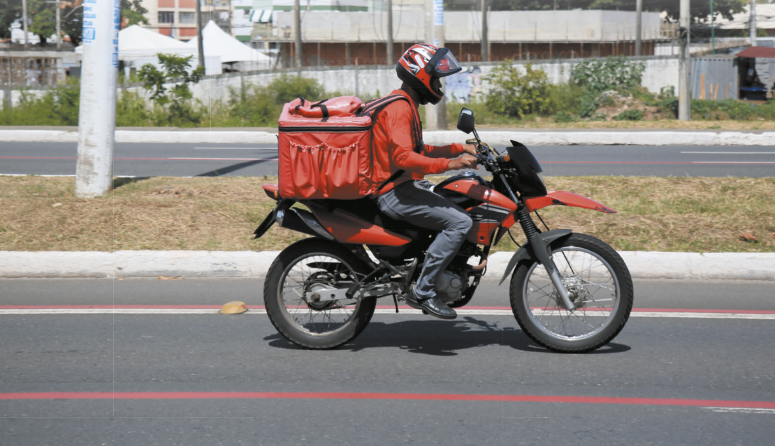 Fotografia de entregador dirigindo moto.