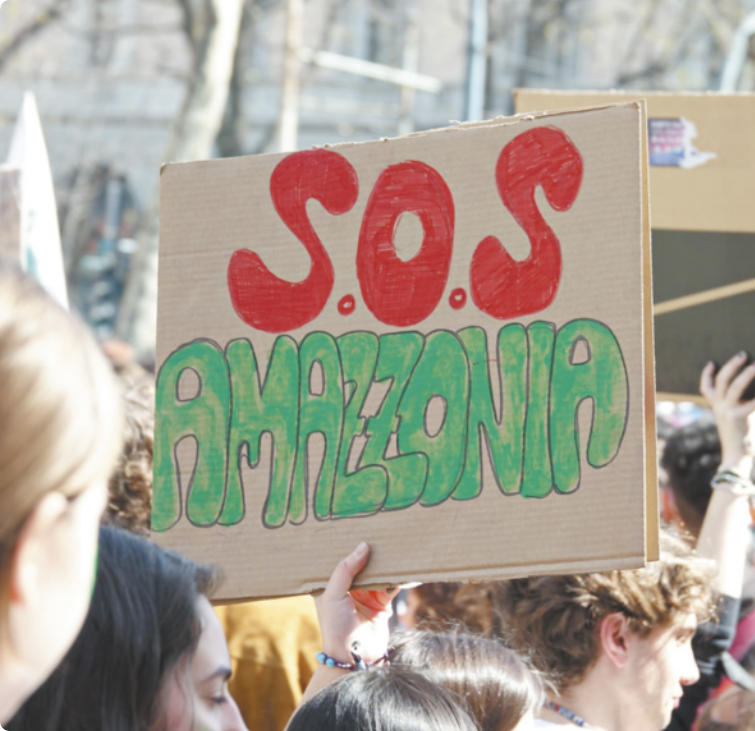 Fotografia de pessoas em protesto segurando cartaz escrito 'S.O.S AMAZÔNIA'.