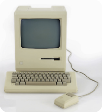 Fotografia de um computador com monitor de tubo apoiado sobre uma CPU horizontal com porta para disquete. Também vemos o teclado e o mouse com fio.
