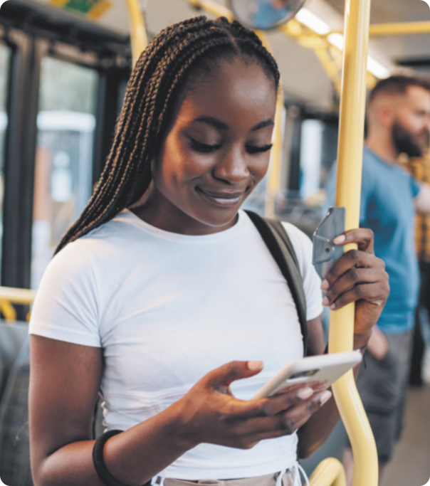 Fotografia de uma mulher dentro de um ônibus olhando para seu smartphone.
