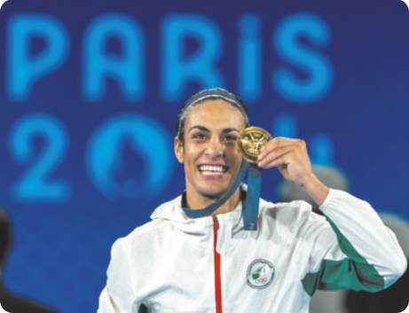 Fotografia de Imane Khelif. Ela é uma atleta com os cabelos presos, sorrindo e exibindo uma medalha de ouro nas mãos.