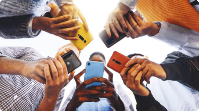 Fotografia de cinco jovens reunidos em roda, segurando smartphones.