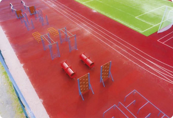 Ilustração de um circuito com diversos tipos de obstáculos, organizados em duas linhas em uma pista de atletismo em volta de um campo de futebol.