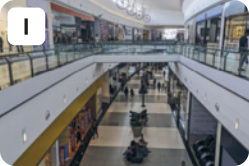 I. Fotografia de lojas e pessoas sentadas e caminhando em um ambiente fechado.