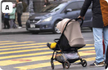 A. Fotografia de uma pessoa segurando um carrinho de bebê e esperando na faixa de pedestres para atravessar uma rua com carros.