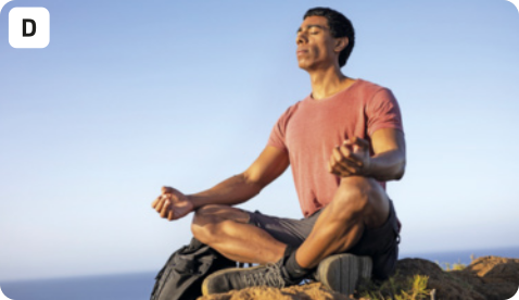 D. Fotografia de um homem em postura meditativa. Ele está sentado com as pernas cruzadas e as mãos apoiadas nos joelhos, e tem os olhos fechados e uma expressão tranquila. O cenário aparenta ser o alto de uma montanha, e o céu está azul.