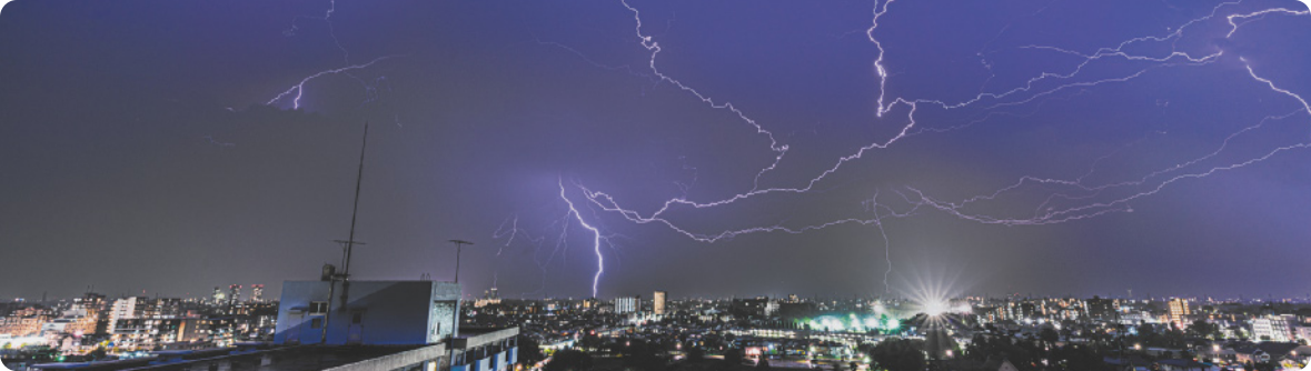 Fotografia do céu de uma cidade à noite, com raios iluminados.