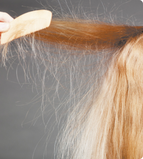 Fotografia de um pente passando sobre uma mecha de cabelo, arrepiando com a eletrostática.