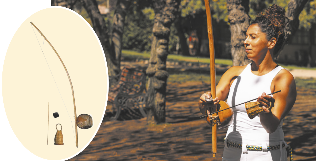 Fotografia de uma pessoa tocando berimbau. Ela está em pé segurando o instrumento, ao fundo árvores. Uma ilustração de um berimbau está em destaque, sobreposta na imagem principal. Imagem de uma vara longa de madeira, com um fio amarrado nas extremidades, envergando a vara. Inserido na vara uma esfera de madeira oca aberta. Um chocalho de palha com alça está na imagem.