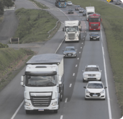 Fotografia de veículos trafegando por uma rodovia.
