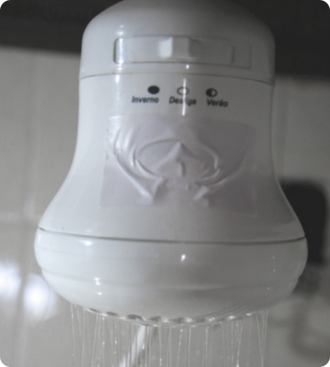 Fotografia de um chuveiro elétrico formato circular, com botão de temperatura, saindo água.