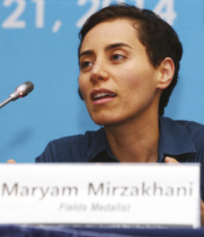 Fotografia de Maryam Mirzakhani. Ela é uma mulher branca, de cabelos curtos e escuros, sentada atrás de uma mesa com um microfone à sua frente. Sobre a mesa, há uma placa com o texto: 'Maryam Mirzakhani – Fields Medalist'. O fundo da imagem é azul, com textos desfocados ao fundo.