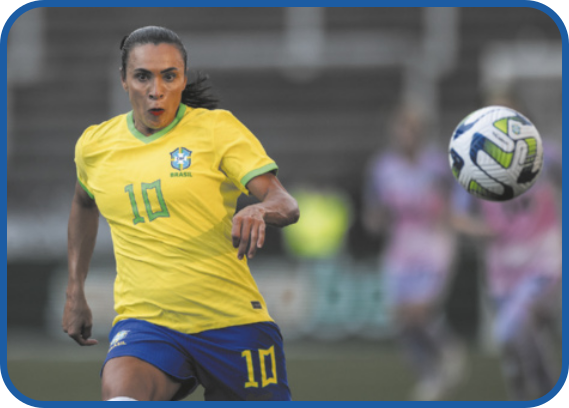 Fotografia de Marta Silva durante uma partida de futebol, correndo em direção a uma bola. Ela tem cabelos pretos presos para trás e veste o uniforme da seleção brasileira: camiseta amarela e shorts azul, ambos com o número 10 estampado.