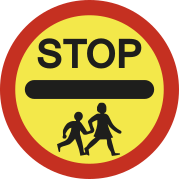 Imagem de uma placa de trânsito em formato circular, com borda vermelha e fundo amarelo. Na parte superior está escrito em preto a palavra 'STOP', logo abaixo há uma faixa preta horizontal e, na parte inferior, o desenho de duas pessoas caminhando de mãos dadas.