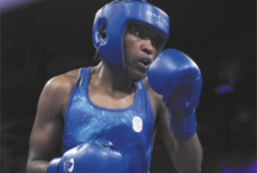 Fotografia de Cindy Ngamba. Ela é negra, está usando capacete e luvas de boxe, protetor bucal e uma regata.