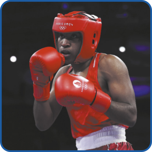 Fotografia de Cindy Ngamba lutando boxe. Ela é negra e está usando luvas de boxe, capacete de proteção, regata e shorts.