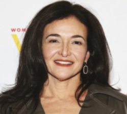 Fotografia de Sheryl Sandberg. Ela é uma mulher branca, está sorrindo, tem cabelos castanhos, lisos e longos e usa brinco.