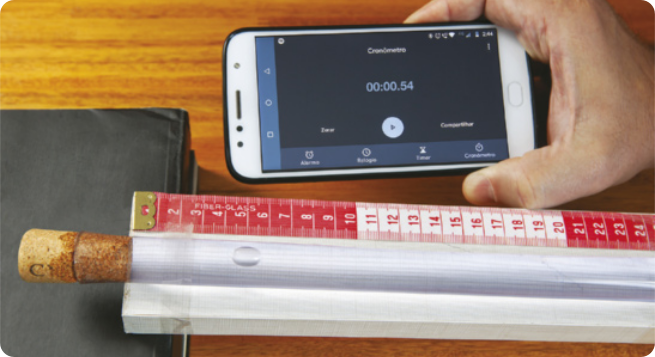 Fotografia anterior. Agora temos a mão de uma pessoa segurando um smartphone, com a tela exibindo um cronômetro em funcionamento.