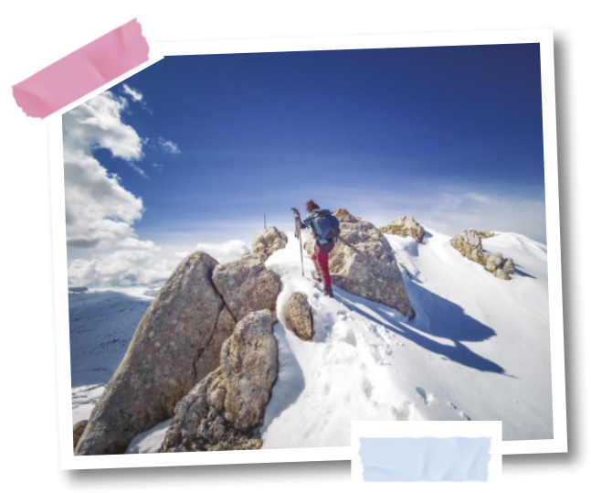 Fotografia de um escalador no topo de uma montanha com neve.