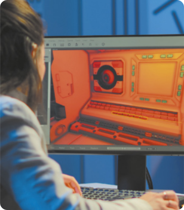 Fotografia de uma jovem olhando para a tela de um computador, na qual há um cenário em 3D.