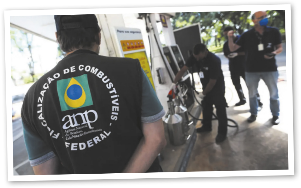 Fotografia da área de abastecimento de um posto de combustível. À esquerda, um homem em destaque aparece de costas, usando um colete com a inscrição “Fiscalização de Combustíveis, Federal” e um logotipo centralizado. À direita e ao fundo, 3 homens estão próximos a uma bomba de combustível: um deles manuseia a bomba, enquanto os outros observam. Um deles segura um celular.