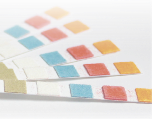 Fotografia de tiras de papéis. Sobre as tiras há quatro quadrados com diferentes colorações.