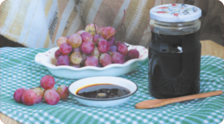 Fotografia de uvas em um prato e de um pote de geleia.