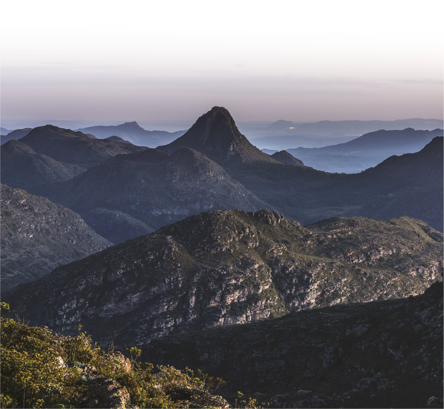 Fotografia aérea de montanhas. Há névoa em parte de sua superfície.