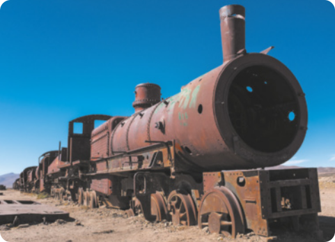 Fotografia de um trem. Sua estrutura de ferro está coberta por ferrugem.