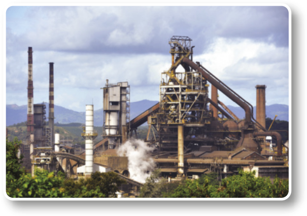Fotografia de grande construção industrial com chaminés e dutos.