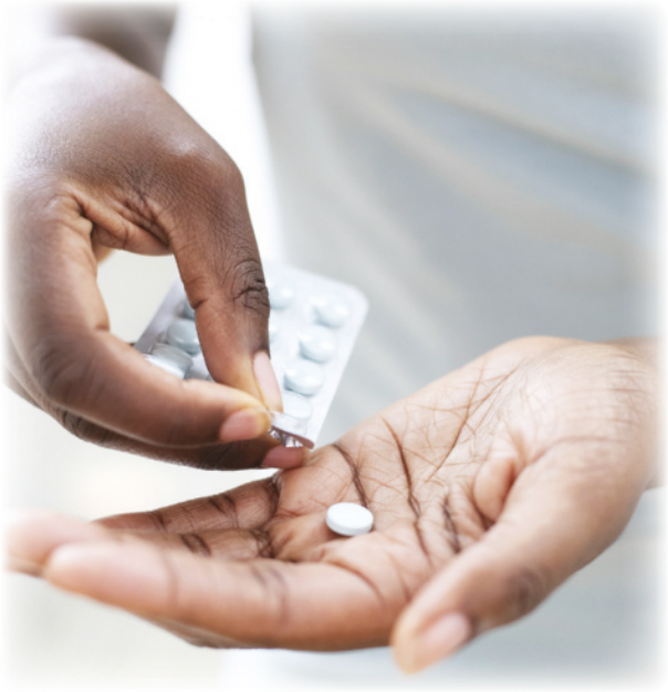 Fotografia de duas mãos com uma cartela de medicamento. Uma das mãos pressiona a cartela, enquanto a outra está abaixo, segurando o comprimido.