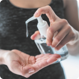 Fotografia de pessoa manuseando um frasco com álcool em gel. O recipiente está posicionada sobre uma das mãos e, com a outra, ela pressiona a válvula.