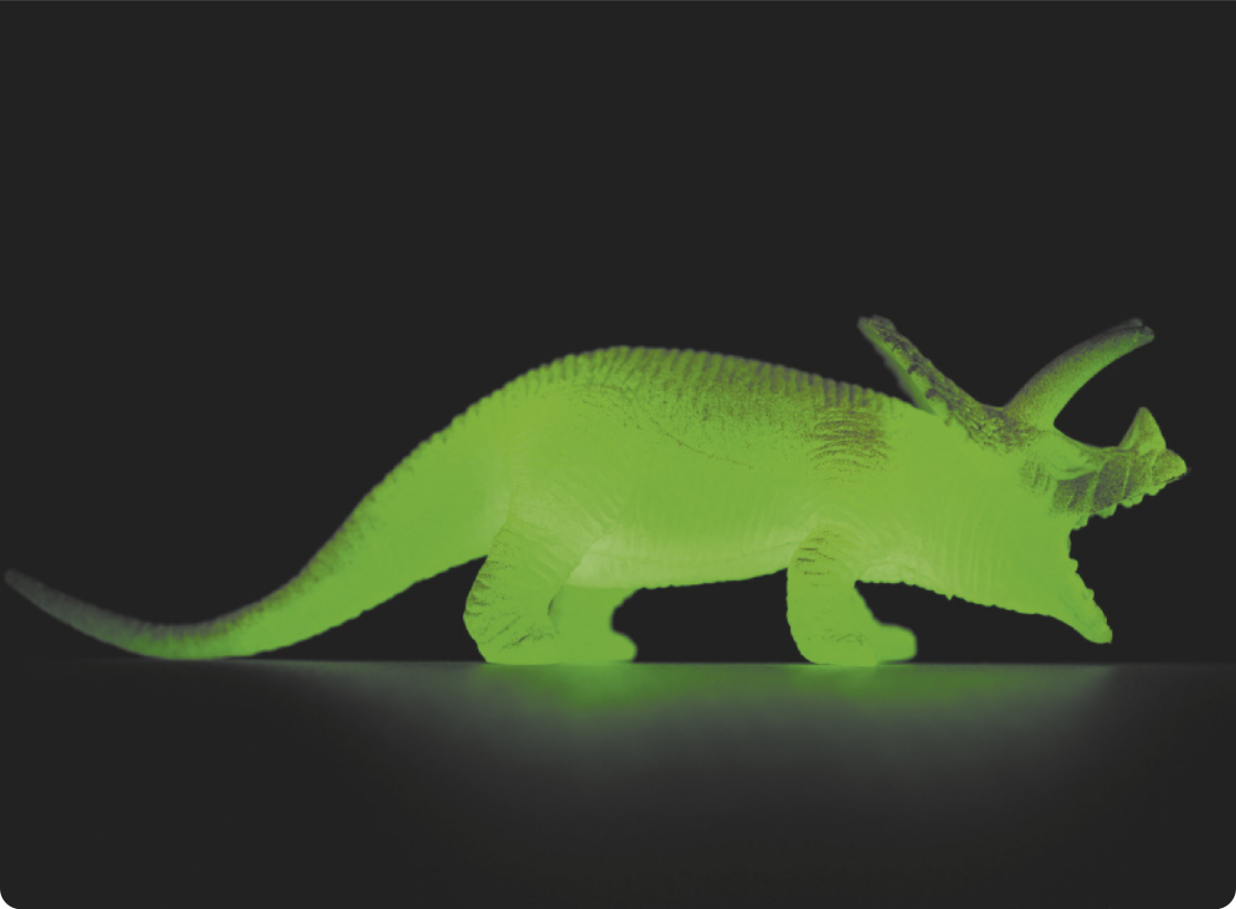 Fotografia de um dinossauro de brinquedo brilhando no escuro.