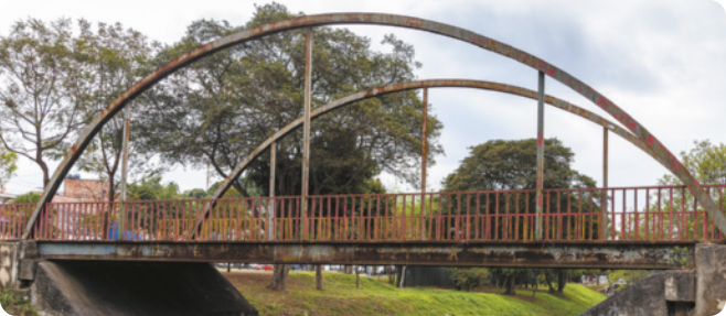 Fotografia de uma ponte de metal, com manchas de ferrugem.