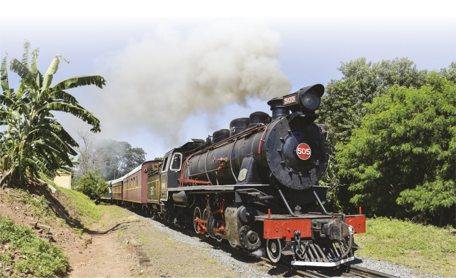 Fotografia de uma locomotiva em movimento, com fumaça saindo da chaminé.